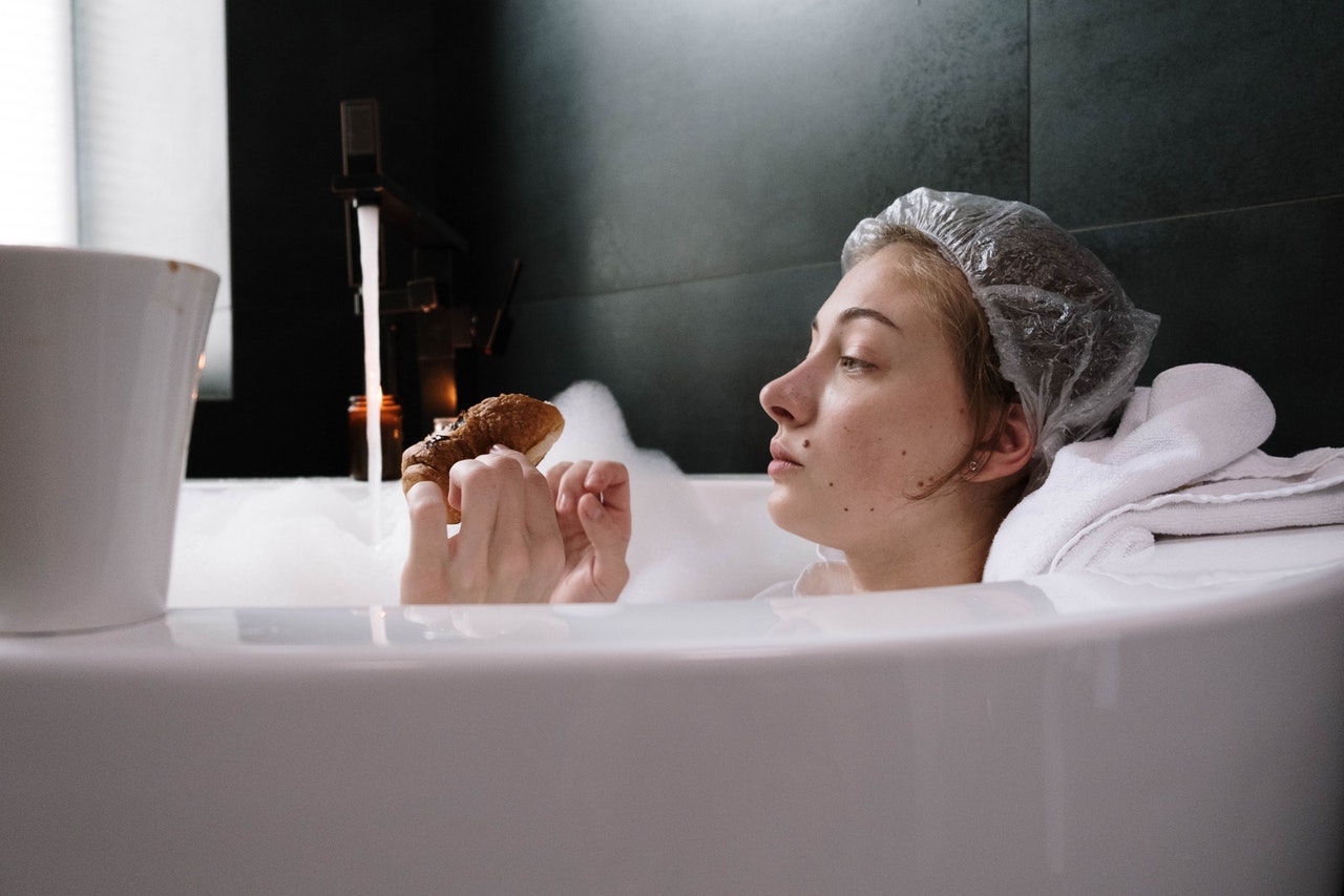 Woman is taking a bathn using a shower cap
